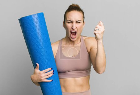 Foto de Young pretty woman shouting aggressively with an angry expression. fitness and yoga concept - Imagen libre de derechos