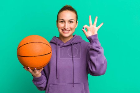Photo for Young pretty woman feeling happy, showing approval with okay gesture. basketball concept - Royalty Free Image