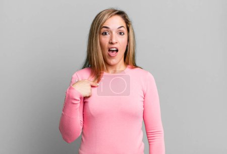 Téléchargez les photos : Blonde adult woman looking shocked and surprised with mouth wide open, pointing to self - en image libre de droit