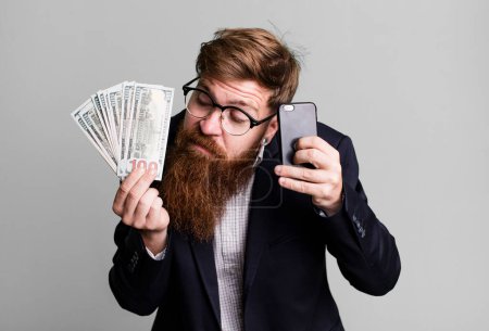 Foto de Joven adulto pelo rojo barbudo fresco hombre de negocios con facturas y un teléfono - Imagen libre de derechos