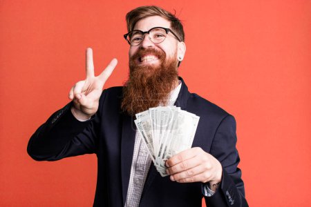 Téléchargez les photos : Jeune adulte cheveux roux barbu cool homme d'affaires avec des billets de banque - en image libre de droit