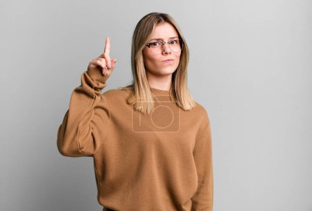 Photo for Blonde pretty woman feeling like a genius holding finger proudly up in the air after realizing a great idea, saying eureka - Royalty Free Image