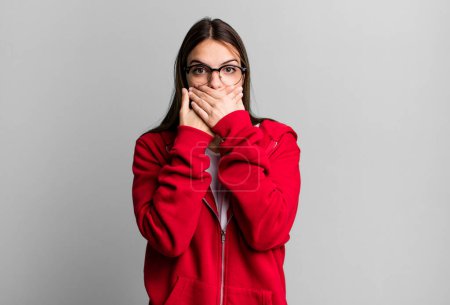 Téléchargez les photos : Pretty young adult woman covering mouth with hands with a shocked, surprised expression, keeping a secret or saying oops - en image libre de droit