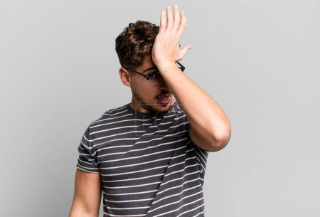 Téléchargez les photos : Young adult caucasian man raising palm to forehead thinking oops, after making a stupid mistake or remembering, feeling dumb - en image libre de droit