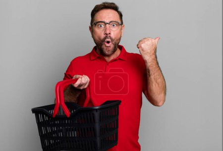 Photo for Middle age man looking astonished in disbelief. empty shopping basket concept - Royalty Free Image