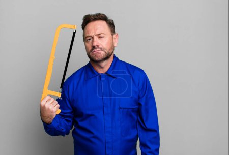 Photo for Middle age repairman with a hand saw sport coach concept with a soccer ball - Royalty Free Image