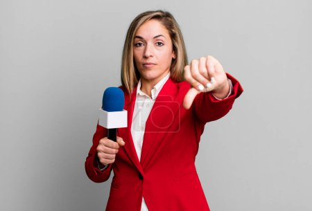 Foto de Pretty blonde woman feeling cross,showing thumbs down. presenter with a microphone concept - Imagen libre de derechos
