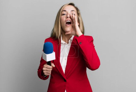 Photo for Pretty blonde woman feeling happy,giving a big shout out with hands next to mouth. presenter with a microphone concept - Royalty Free Image