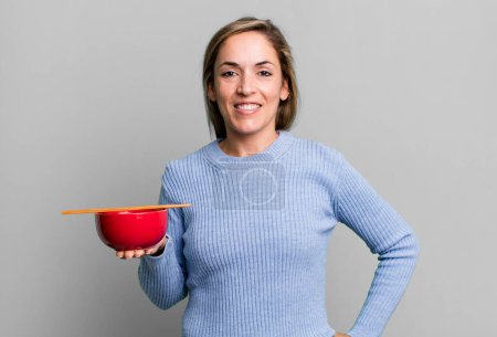 Photo for Pretty blonde woman smiling happily with a hand on hip and confident. japanese noodles concept - Royalty Free Image