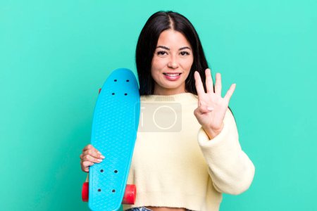 Foto de Hispanic pretty woman smiling and looking friendly, showing number four. skate boarding concept - Imagen libre de derechos