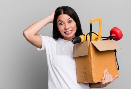 Photo for Hispanic pretty woman feeling stressed, anxious or scared, with hands on head with a tool box - Royalty Free Image