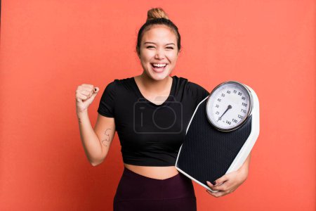 Téléchargez les photos : Hispanic pretty woman feeling shocked,laughing and celebrating success. fitness and diet concept - en image libre de droit