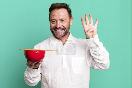 Photo for Middle age man smiling and looking friendly, showing number four. breakfast bowl - Royalty Free Image