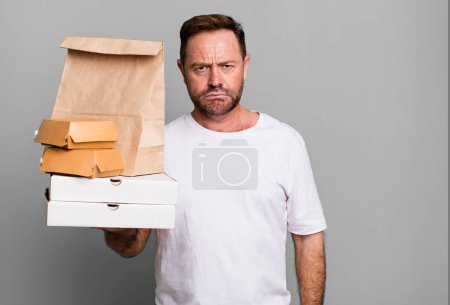 Téléchargez les photos : Middle age man feeling sad and whiney with an unhappy look and crying. delivery and fast food take away concept - en image libre de droit