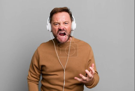 Foto de Hombre de mediana edad que parece enojado, molesto y frustrado. escuchar música con auriculares - Imagen libre de derechos