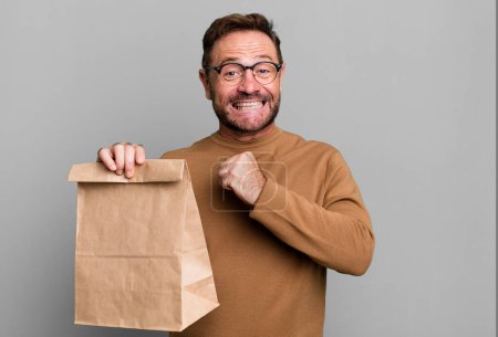 Téléchargez les photos : Homme d'âge moyen se sentir heureux et faire face à un défi ou célébrer. emporter sac en papier - en image libre de droit