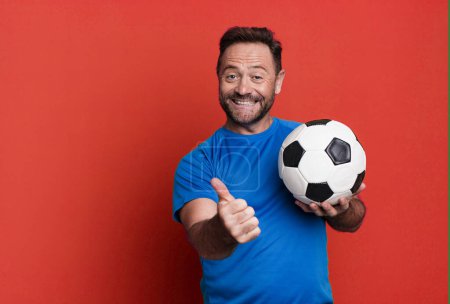Téléchargez les photos : Middle age man feeling proud,smiling positively with thumbs up. with a soccer ball. fitness concept - en image libre de droit