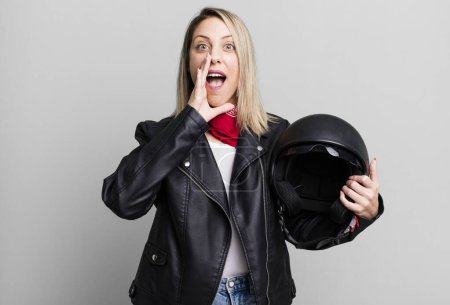 Photo for Pretty blonde woman feeling happy,giving a big shout out with hands next to mouth. motorbike rider and helmet concept - Royalty Free Image