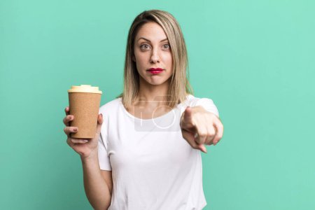 Téléchargez les photos : Pretty blonde woman pointing at camera choosing you with a hot coffee - en image libre de droit