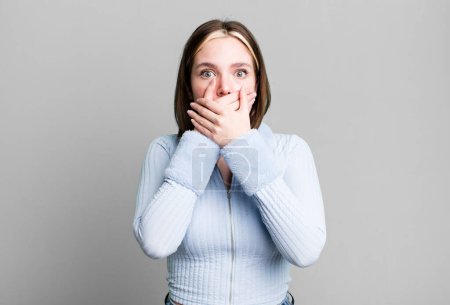 Photo for Young pretty woman covering mouth with hands with a shocked - Royalty Free Image