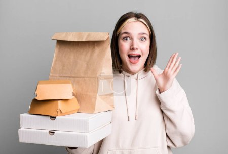 Photo for Young pretty woman feeling happy and astonished at something unbelievable. take away fast food concept - Royalty Free Image