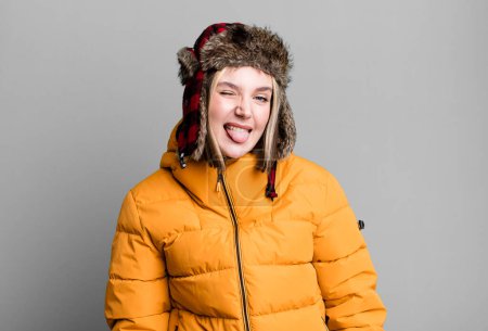 Téléchargez les photos : Young pretty woman with cheerful and rebellious attitude, joking and sticking tongue out. cold and coat concept - en image libre de droit