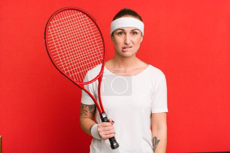 Foto de Joven bonita mujer buscando desconcertado y confundido. concepto de tenis - Imagen libre de derechos