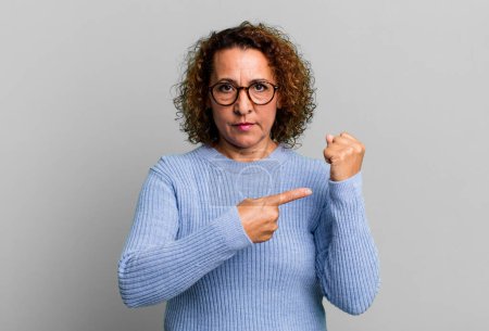 Photo for Middle age hispanic woman looking impatient and angry, pointing at watch, asking for punctuality, wants to be on time - Royalty Free Image