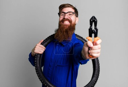 Foto de Joven adulto pelo rojo barbudo fresco reparación hombre con una rueda de bicicleta - Imagen libre de derechos