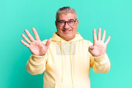 Téléchargez les photos : Homme âgé d'âge moyen souriant et regardant amical, montrant numéro neuf ou neuvième avec la main vers l'avant, compte à rebours - en image libre de droit