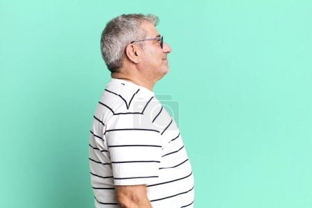 Téléchargez les photos : Homme âgé d'âge moyen sur la vue de profil cherchant à copier l'espace devant, penser, imaginer ou rêver - en image libre de droit