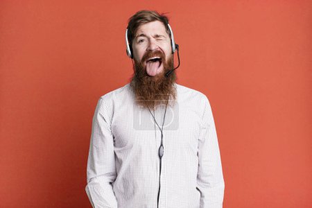 Téléchargez les photos : Homme barbe longue avec une attitude joyeuse et rebelle, plaisanter et sortir la langue. concept d'agent de télémarketing - en image libre de droit