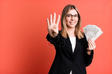 Foto de Joven bonita mujer sonriendo y buscando amigable, mostrando el número cuatro. concepto de negocio y dinero - Imagen libre de derechos