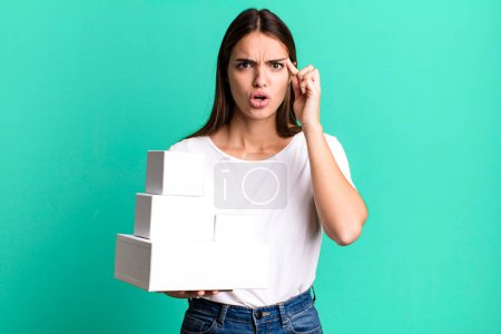 Téléchargez les photos : Young pretty woman looking surprised, realizing a new thought, idea or concept. blank white boxes - en image libre de droit