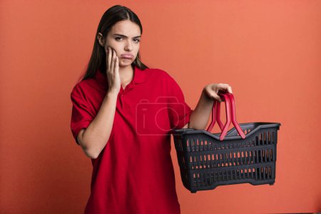 Photo for Young pretty woman feeling bored, frustrated and sleepy after a tiresome. empty shopping basket concept - Royalty Free Image