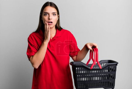 Photo for Young pretty woman feeling shocked and scared. empty shopping basket concept - Royalty Free Image
