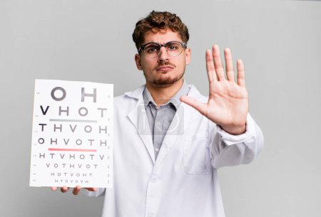 Téléchargez les photos : Young adult caucasian man looking serious showing open palm making stop gesture. optical vision test concept - en image libre de droit