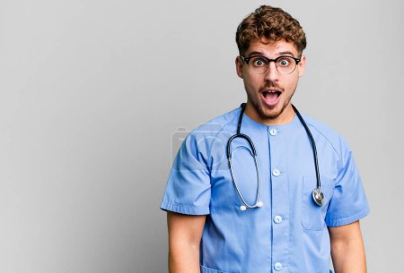 Photo for Young adult caucasian man looking very shocked or surprised. nurse concept - Royalty Free Image