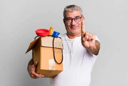 Foto de Hombre mayor de mediana edad sonriendo y mirando amigable, mostrando el número uno. ama de llaves reparador con un concepto de caja de herramientas - Imagen libre de derechos