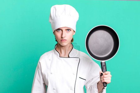 Foto de Caucasian pretty blonde woman. chef with a frying pan concept - Imagen libre de derechos