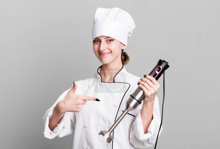 Foto de Caucasian pretty blonde woman. chef concept with a hand mixer - Imagen libre de derechos