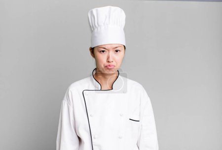 Photo for Pretty asian woman feeling sad and whiney with an unhappy look and crying. restaurant chef concept - Royalty Free Image