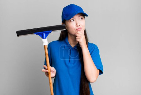 Photo for Pretty asian woman thinking, feeling doubtful and confused. windows cleaning concept - Royalty Free Image