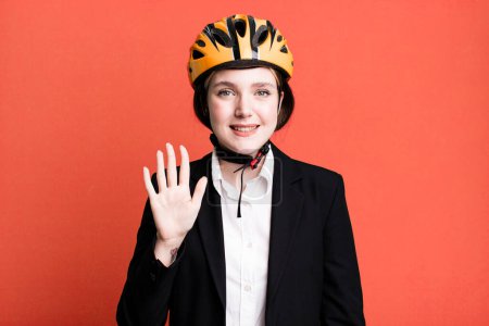 Photo for Young pretty woman smiling and looking friendly, showing number five. bike and businesswoman concept - Royalty Free Image