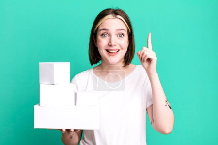 Photo for Young pretty woman feeling like a happy and excited genius after realizing an idea. white blank boxes - Royalty Free Image