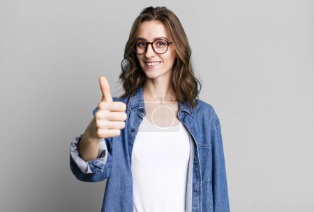 Photo for Young pretty woman feeling proud,smiling positively with thumbs up - Royalty Free Image