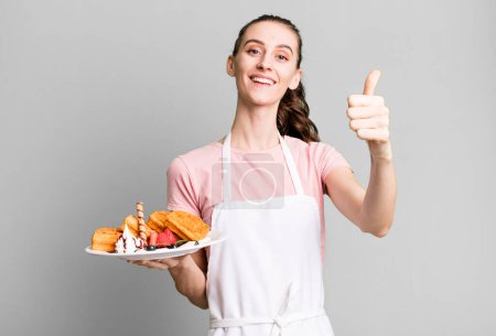 Photo for Young pretty woman feeling proud,smiling positively with thumbs up. waffles concept - Royalty Free Image