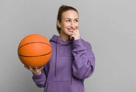 Foto de Joven mujer bonita sonriendo con una expresión feliz y segura con la mano en la barbilla. concepto de baloncesto - Imagen libre de derechos