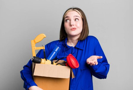 Téléchargez les photos : Young pretty woman shrugging, feeling confused and uncertain. housekeeper and toolbox concept - en image libre de droit