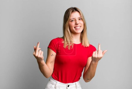 Foto de Rubia bonita mujer sintiéndose provocativa, agresiva y obscena, volteando el dedo medio, con una actitud rebelde - Imagen libre de derechos